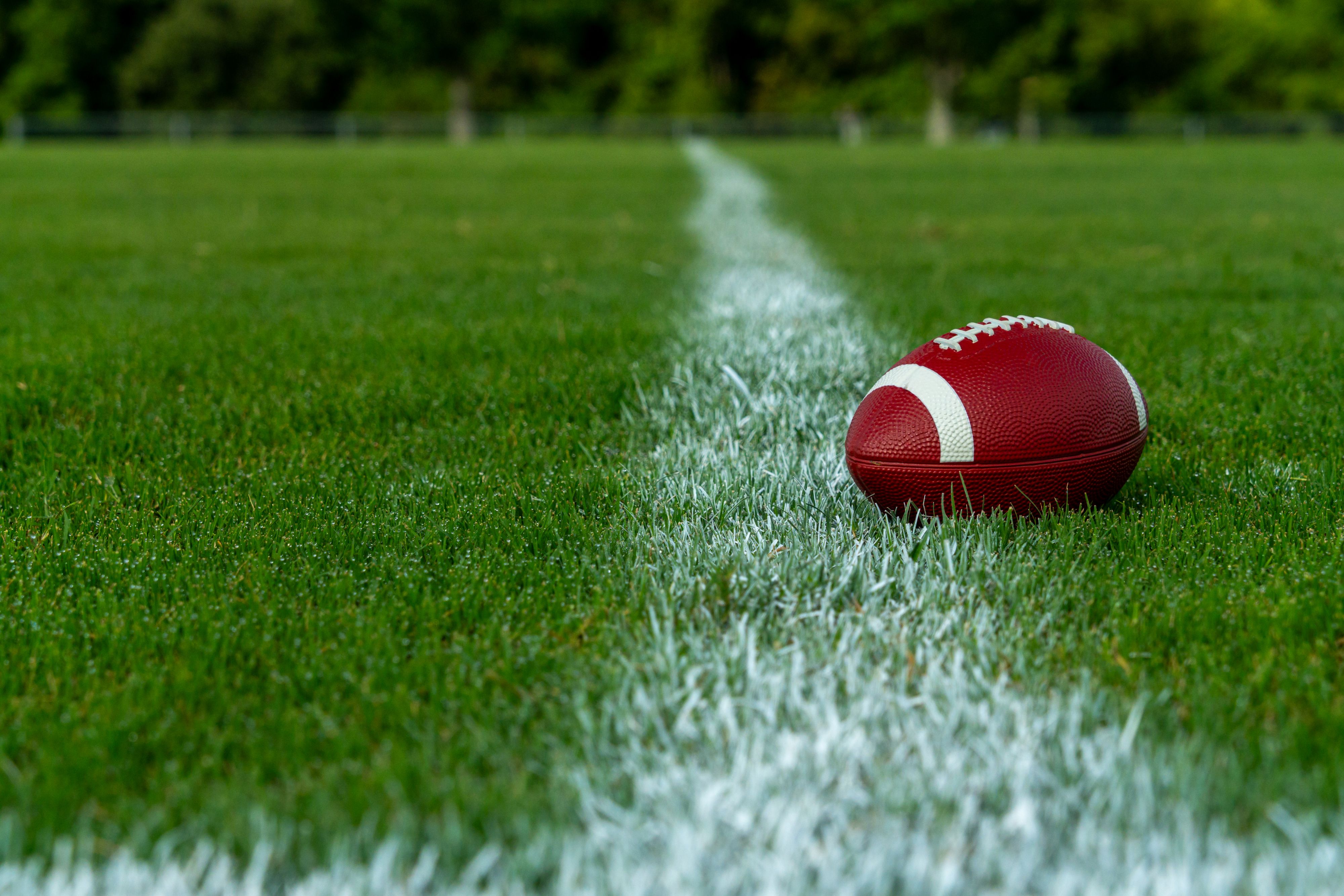 A football lies in a football field of a local public park with lots of copy space